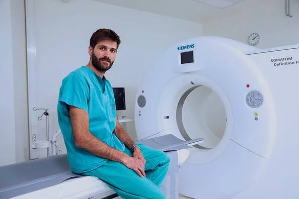 Healthcare professional beside a CT scanner